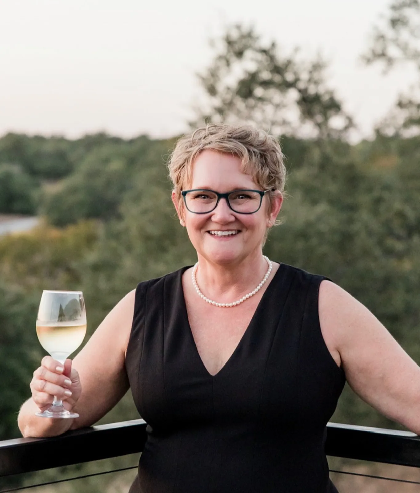 woman in a black dress holding a glass of white wine